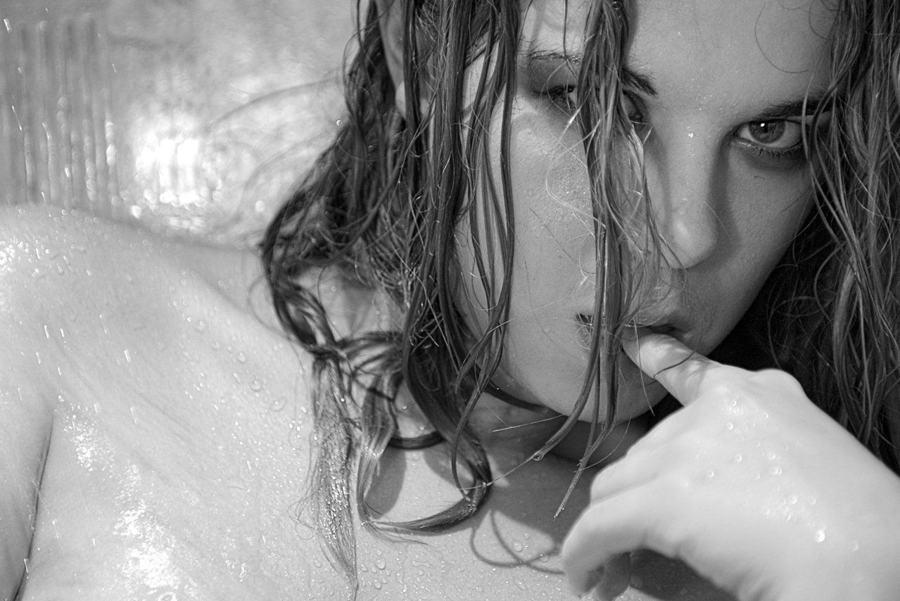 Portrait noir et blanc  de face de Cindy de secret story 3, sous la douche, un doigt dans la bouche.