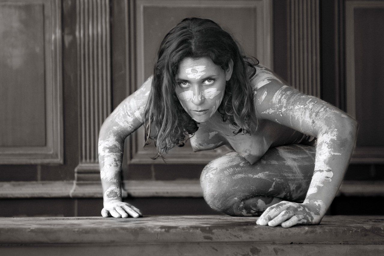 Thierry Aguiar : Photo de Deborah nue le corps maquillé en guerrière à genoux de face  en appui sur les mains sur un comptoir