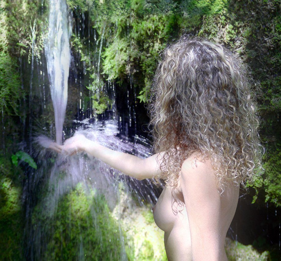 Thierry Aguiar : photo de Luna nue en portrait américain,  la main droite étendue devant elle sous une cascade.