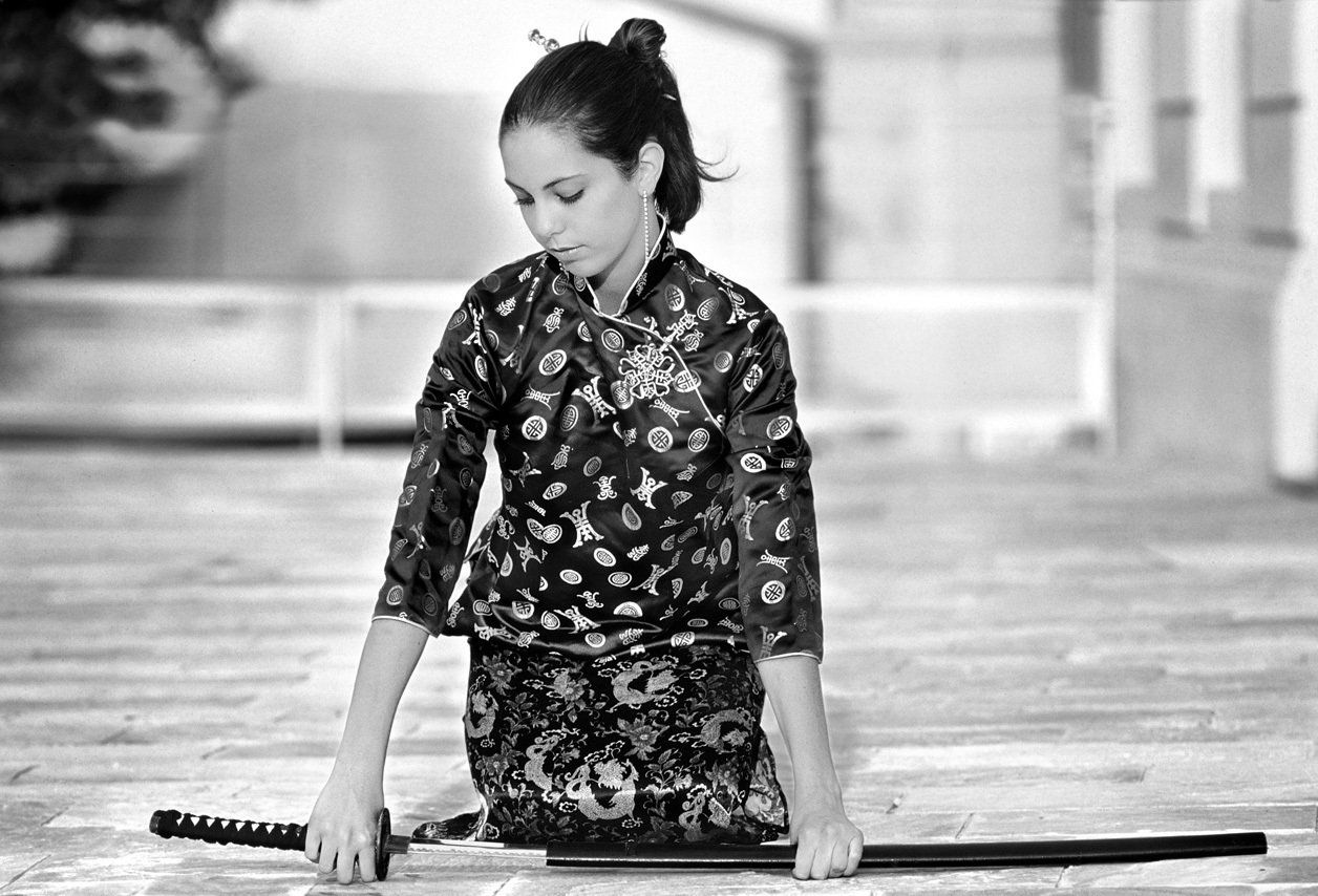 Aguiar Thierry : photo noir et blanc d'Emilie en japonaise, à genoux de face, les mains posées sur un Katana.