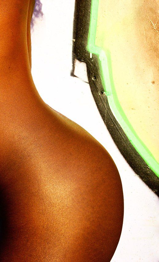 Courbure de la chute de reins de Jessyca  devant un mur avec un tag rond doré bordé de noir.  Parue dans le Magazine PHOTO.