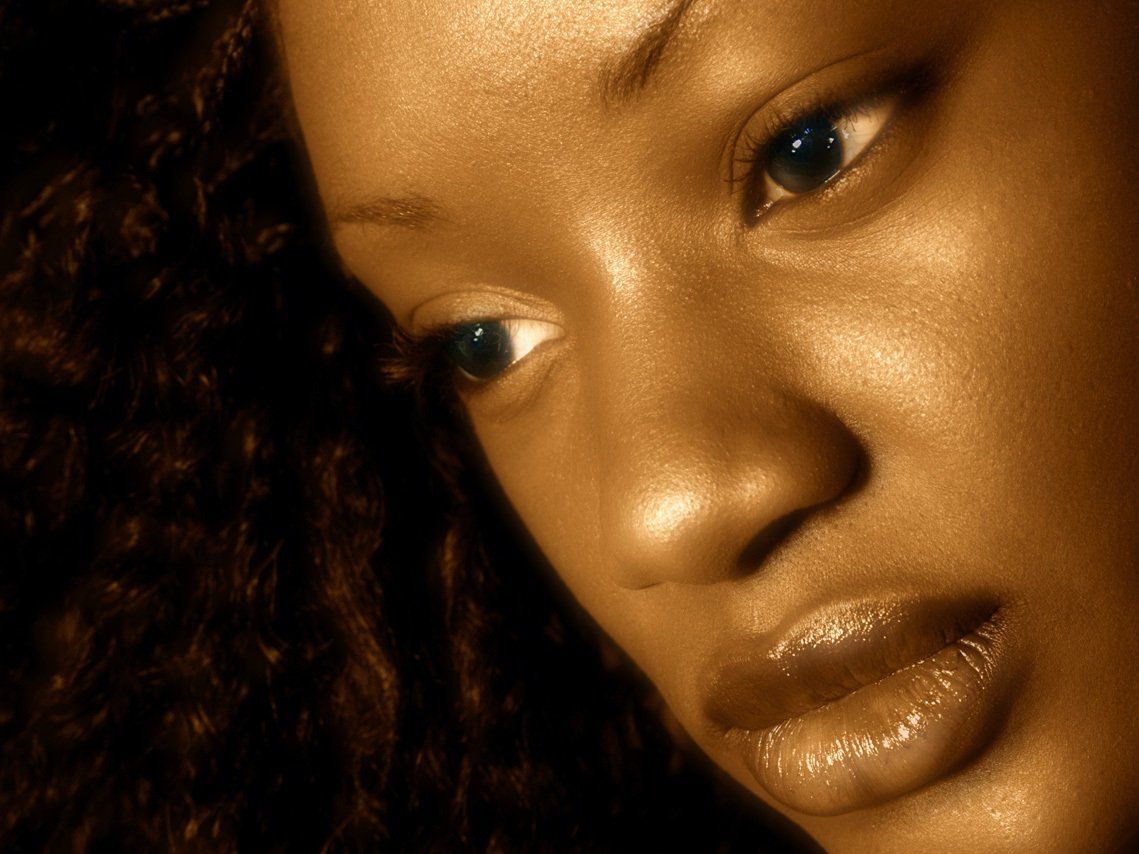 Portrait de trois-quarts en lumière naturelle de Jessyca, jeuen fille noire d'origine congolaise, en intérieur, visage penché vers le bas.