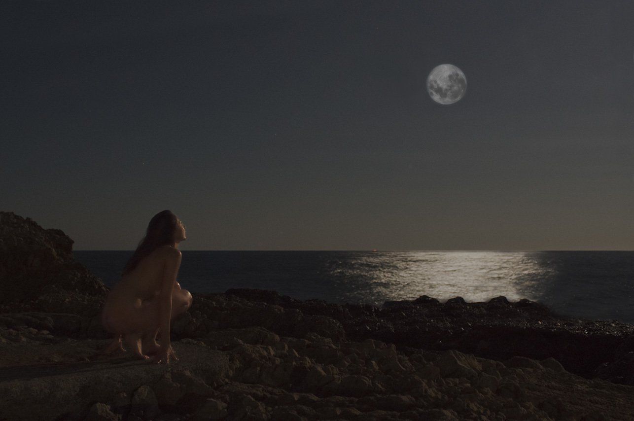 Thierry Aguiar : photo de Juliana nue, de profil, accroupie sur des rochers en bord de mer au Cap d'Antibes, la nuit, éclairée par la lune.