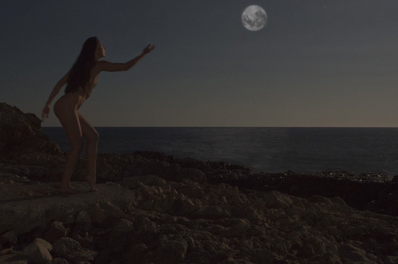 Thierry Aguiar : photo de Juliana nue, de profil, debout sur des rochers en bord de mer au Cap d'Antibes, la nuit, éclairée par la lune.