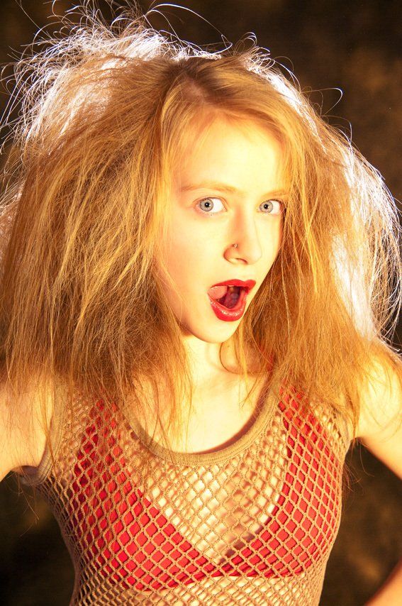 Portrait américain en lumière naturelle de Julie, les mains dans les cheveux, bouche grande ouverte. Photographe Bordeaux.