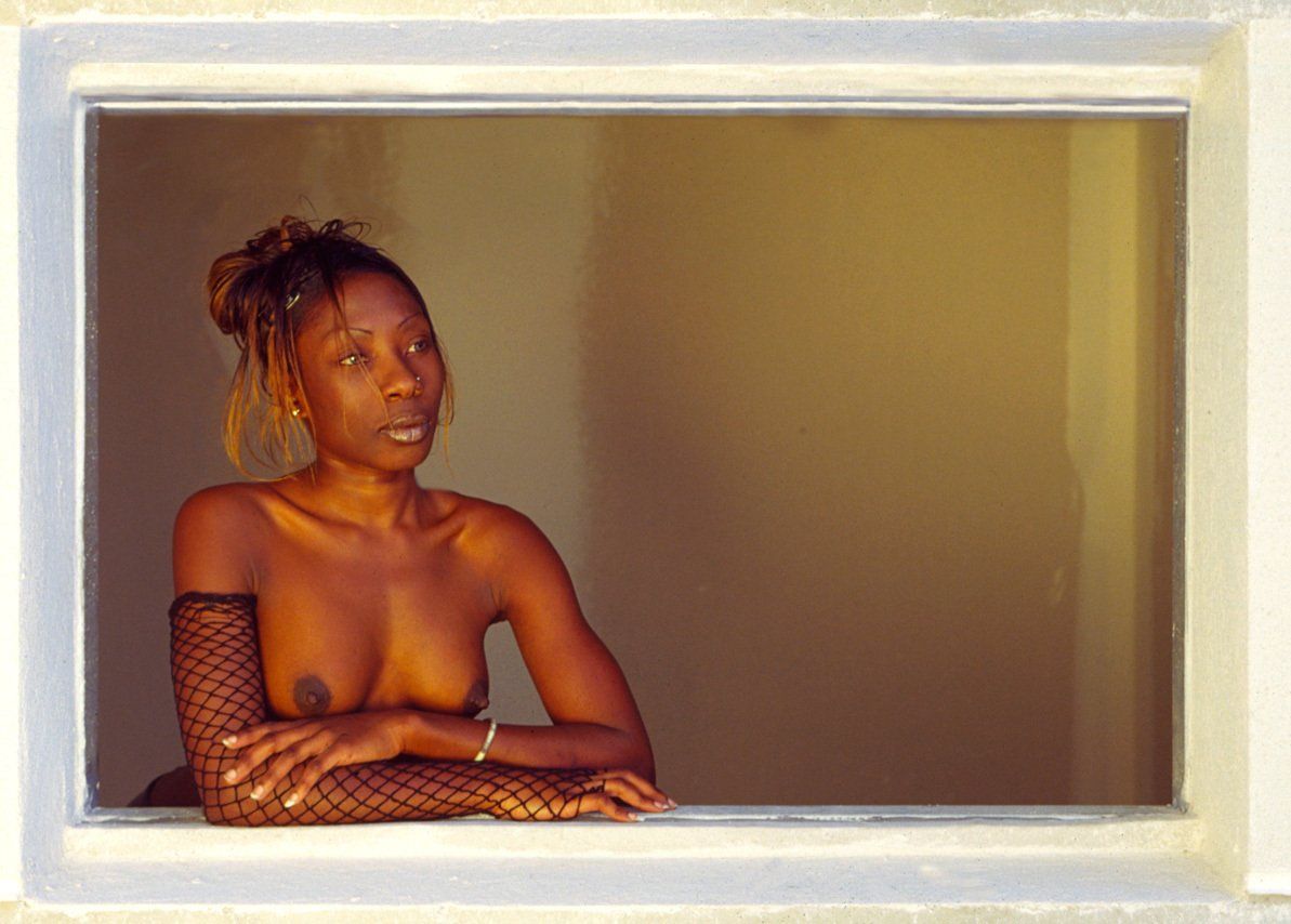 Thierry Aguiar : photo de Maya, jeune fille noire, en topless accoudée à la fenêtre d’une maison en construction.