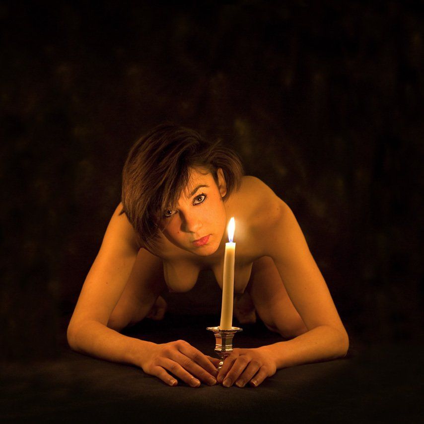 Thierry Aguiar : photo de Pauline nue,  à genoux de face au sol,, éclairée par des bougies, un bougeoir devant elle entre ses mains.