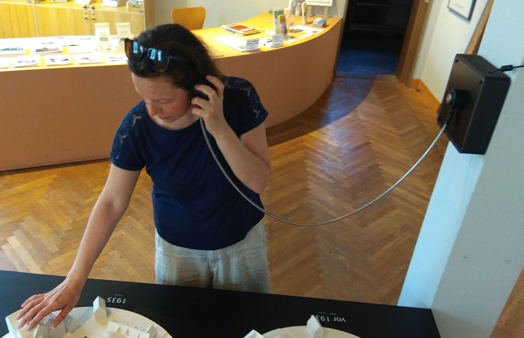 Foto einer Frau, die eine Audiodeskription anhört und ein Modell ertastet