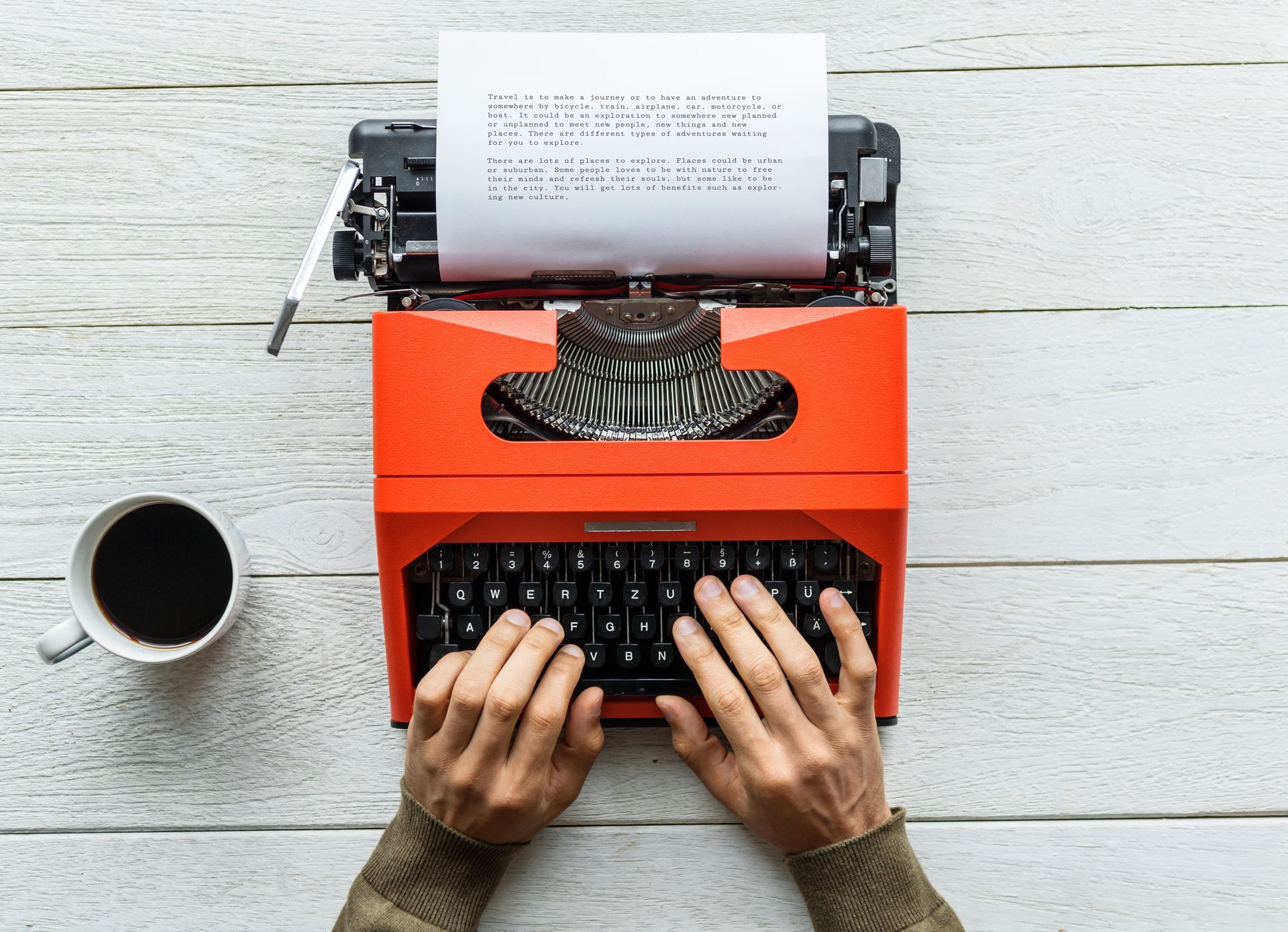 Bild: historische Schreibmaschine mit halb beschriebenem Blatt Papier und zwei tippenden Händen