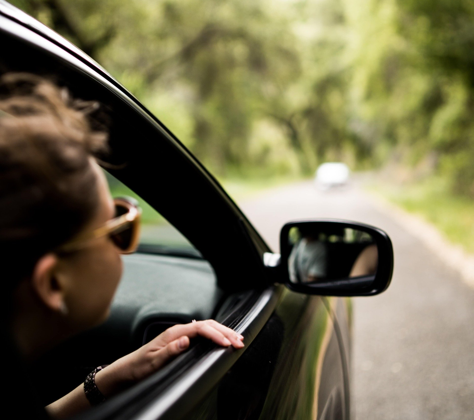 a woman with her head slightly out of a moving car window