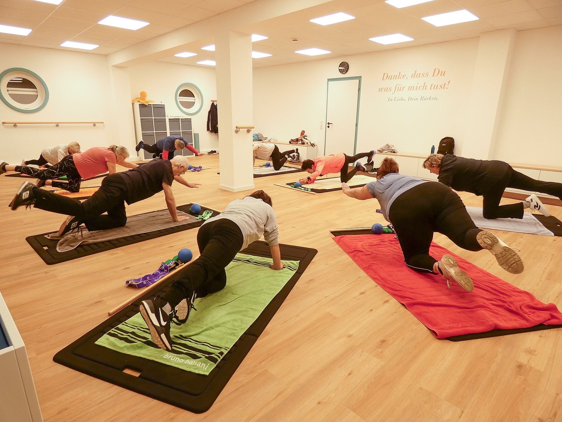 Rückenschule im Seminar- und Bewegungsraum der Reha-Sportgruppe Wardenburg. Die Gruppe übt auf der Matte.