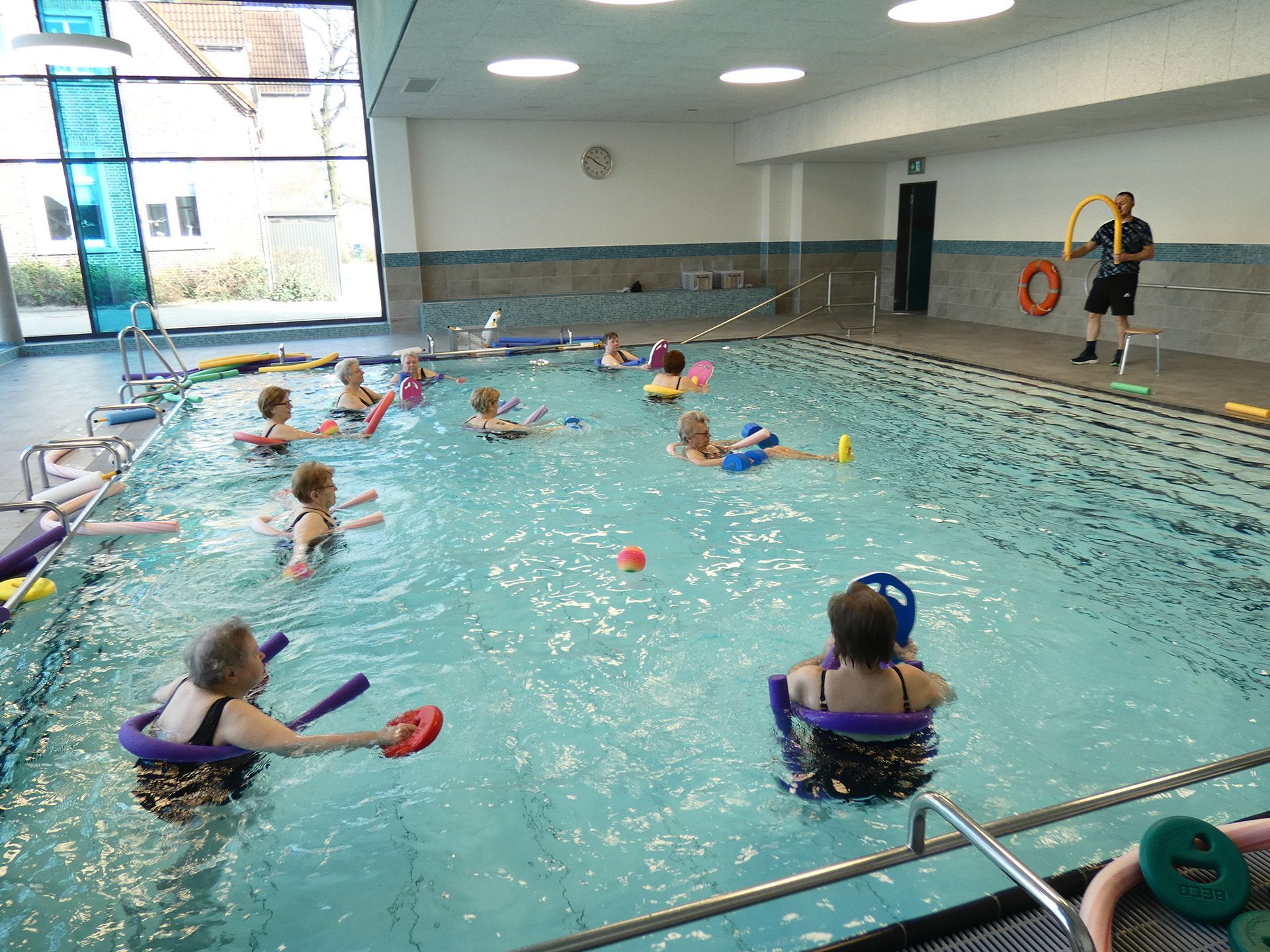 Bildergalerie, Bild 9, Wassergymnastik in der Schwimmhalle in Wardenburg. Eine Gruppe Frauen übt mit Poolnudeln.