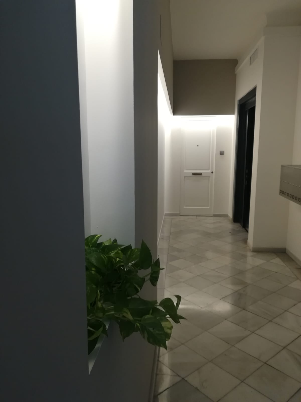 reforma de vestibulo con marmoles y pladur en colores blancos y grises con una led indirecta en el techo