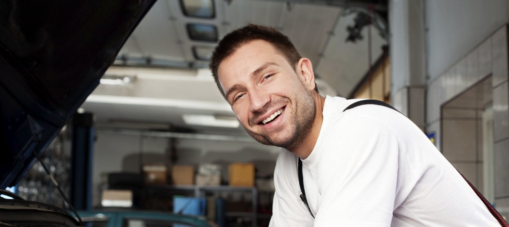 Ein junger Handwerker in einer sauberen Werkstatt lächelt den Betrachter an