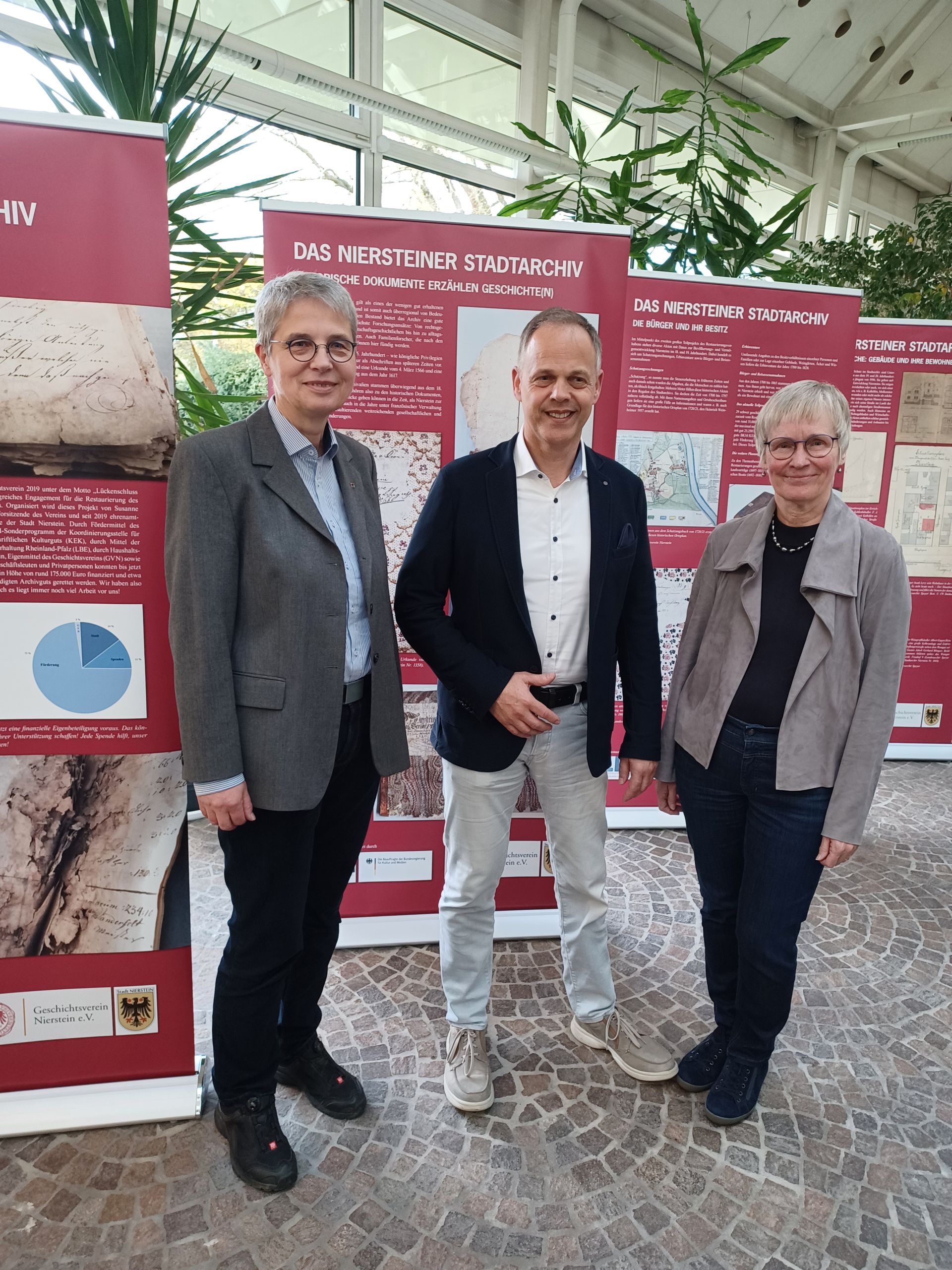 Stadtbürger Schmidt, mit zwei Damen vor rollup mit dem Thema Stadtarchiv Stadtbürger Schmidt, mit zwei Damen vor rollup mit dem Thema Stadtarchiv