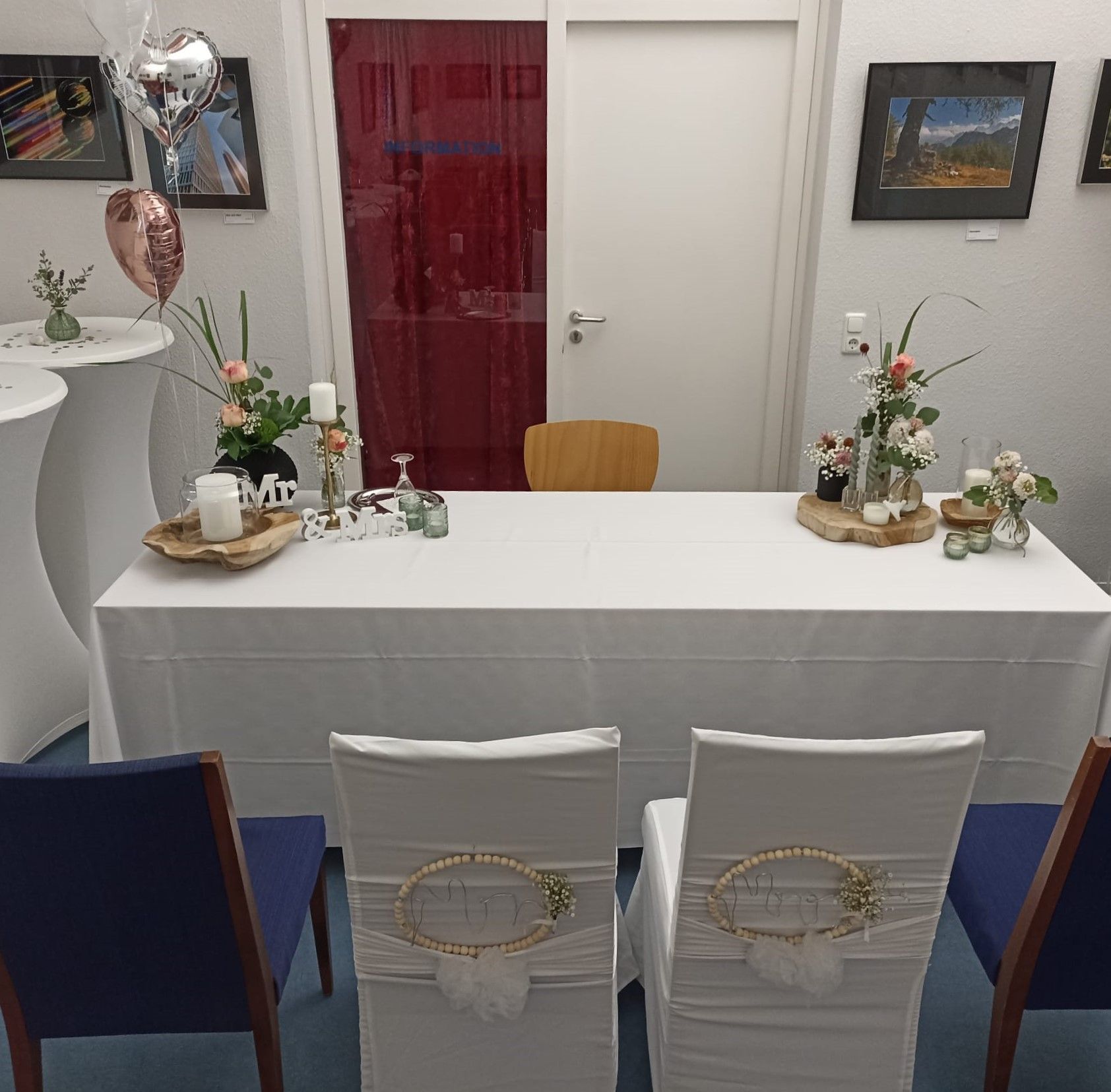 Edel gedeckter Tisch mit 4 Stühlen im Vordergrund und auf der anderen Seite des Tisches ein einzelner Stuhl. Auf dem Tisch steht ein Kerzenhalter und weitere Dekorationsartikel Edel gedeckter Tisch mit 4 Stühlen im Vordergrund und auf der anderen Seite des Tisches ein einzelner Stuhl. Auf dem Tisch steht ein Kerzenhalter und weitere Dekorationsartikel