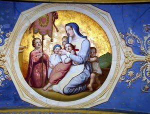 Das Bild zeigt eine religiöse Darstellung innerhalb eines goldumrahmten Medaillons. Im Zentrum kniet eine Frau in Ordenskleidung mit einem roten Kreuz – vermutlich eine Ordensschwester oder Heilige – und umarmt schützend mehrere Kinder. Die Szene strahlt Geborgenheit und Fürsorge aus. Ein Kind hält ein Banner, im Hintergrund sind Hügel zu erkennen. Die leuchtenden Farben und der goldene Hintergrund verleihen dem Bild eine feierliche und ehrfürchtige Atmosphäre. Es könnte sich um eine Darstellung der christlichen Nächstenliebe oder der Schutzpatronin von Waisen oder Kranken handeln.