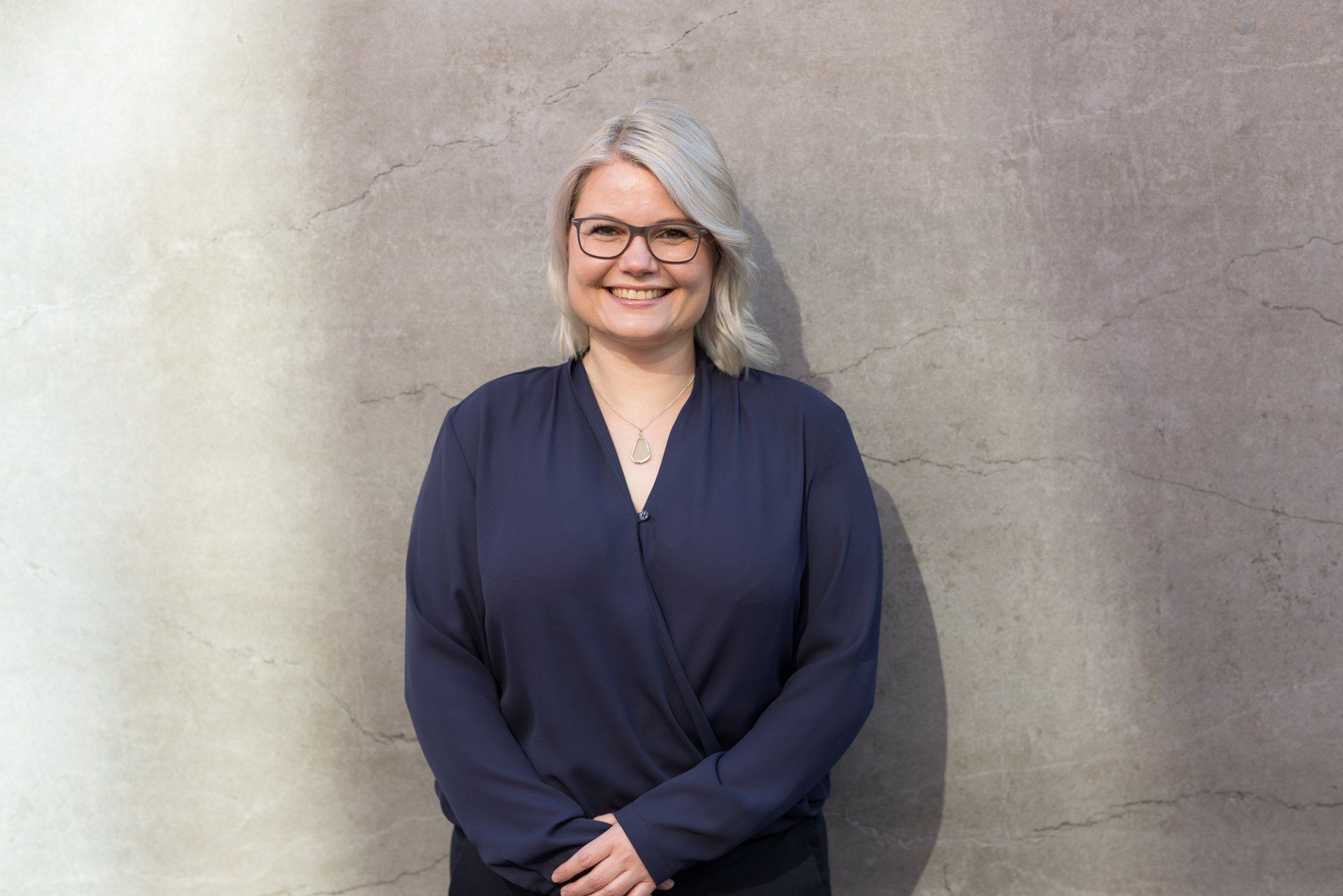 Ein Bild von mir. Ich lehne lächelnd an einer Wand.