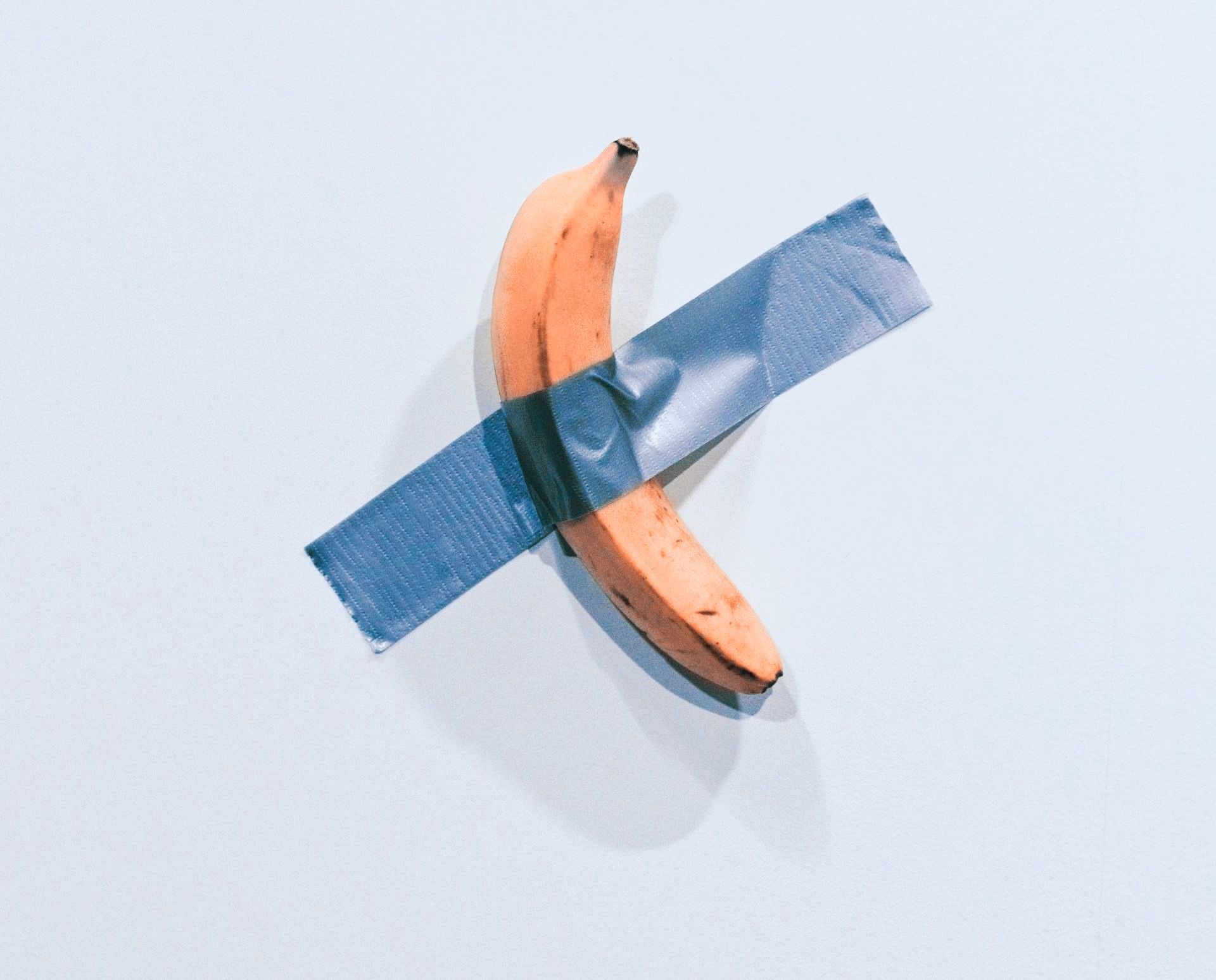 Eine Banane, die mit silbernem Tape an die Wand geglebt ist.