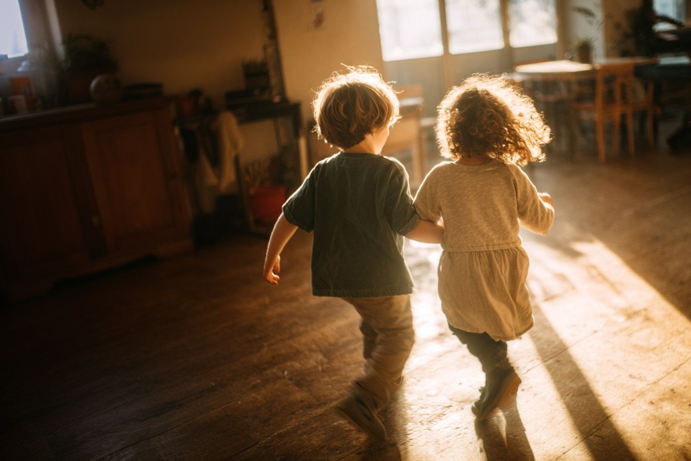 Zwei Kindergartenkinder tanzen gemeinsam im Gruppenraum