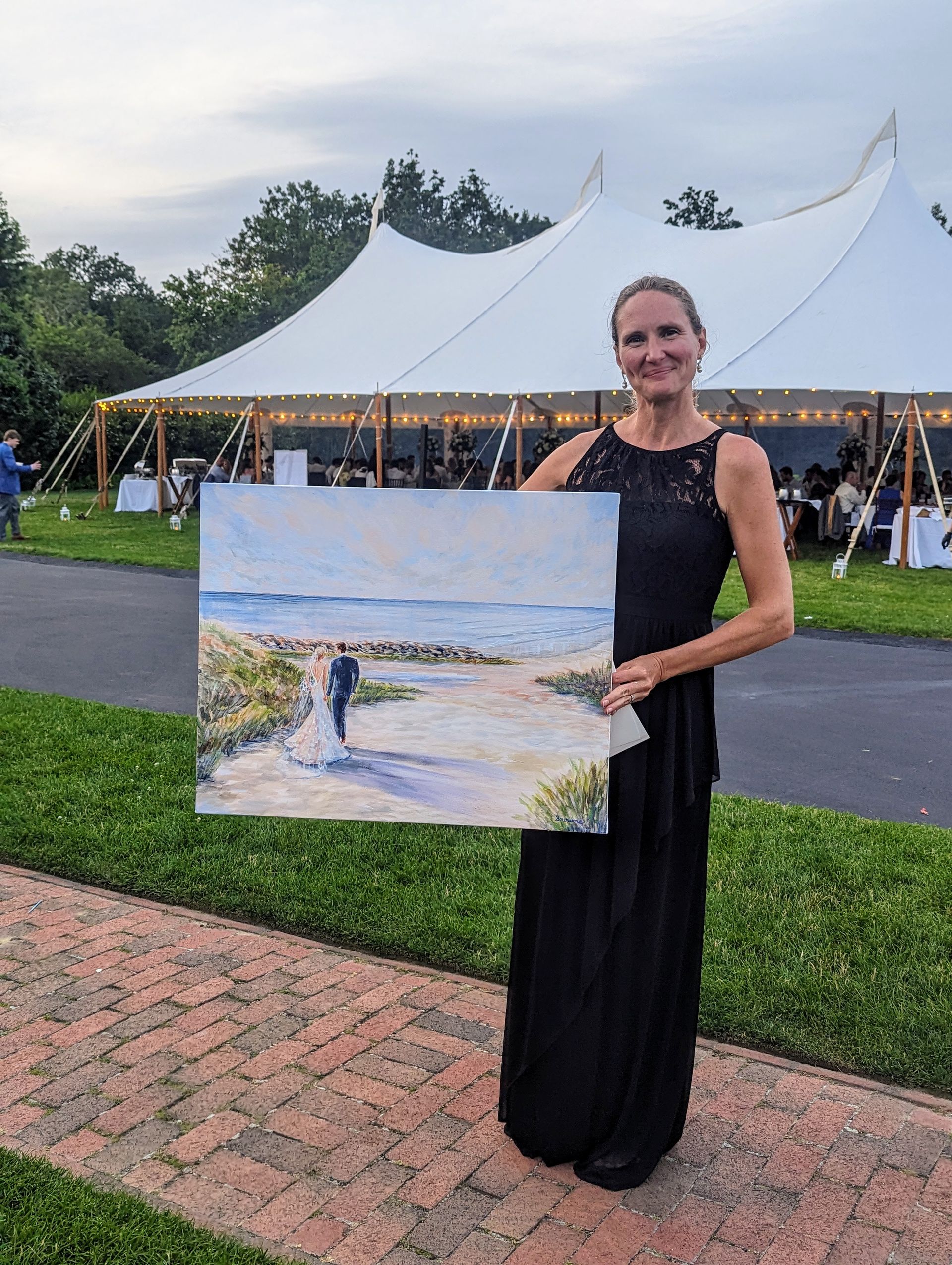Local artist Beth Bee at a tented wedding in MA with her finished painting of the bride and groom at their first look.
