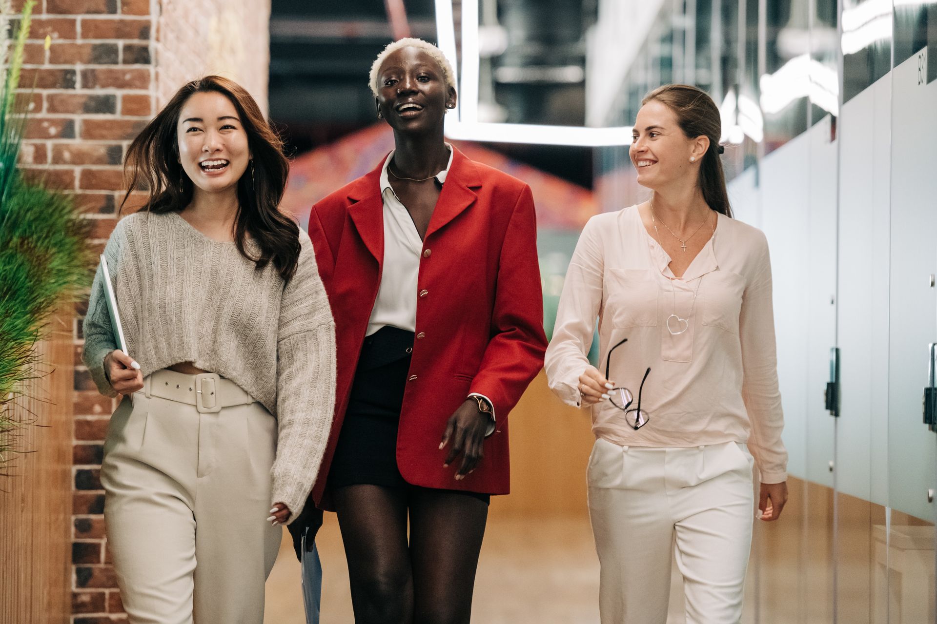 Femmes en vêtements de travail chic discutant dans un espace de bureau.