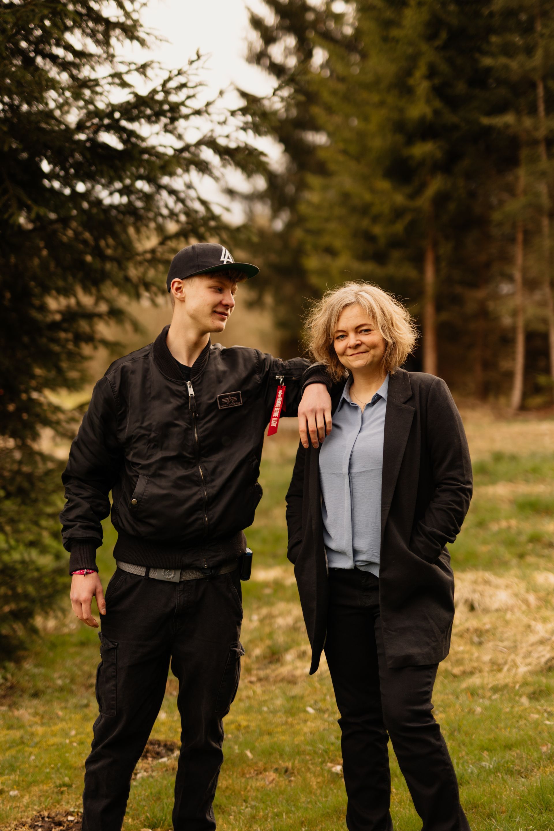 Männlicher Jugendlicher und Daniela Waldert, er hat Arm auf ihrer Schulter abgestützt, er lacht sie an, sie
 lacht in Kamera