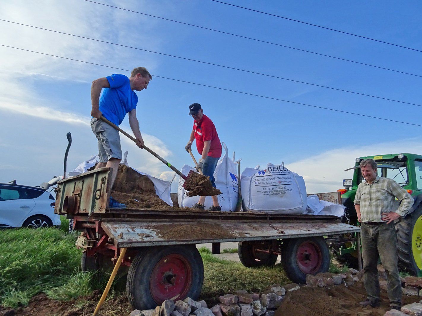 Michael Schuhknecht und Jörg Leinekugel schaufeln den Sand aus dem letzten Sack in die Grube.Sack