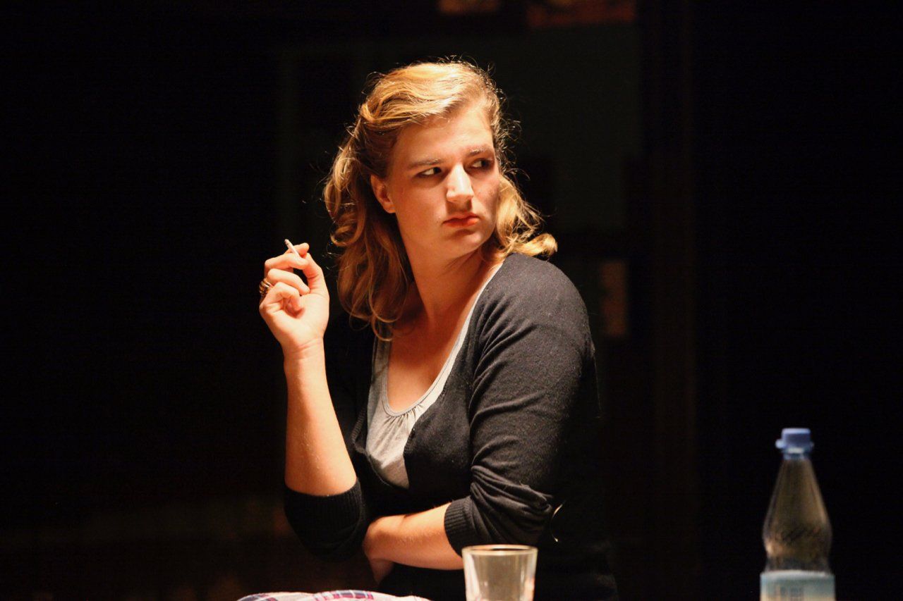 Mujer tomando clases de actuación fumando y con cara crítica