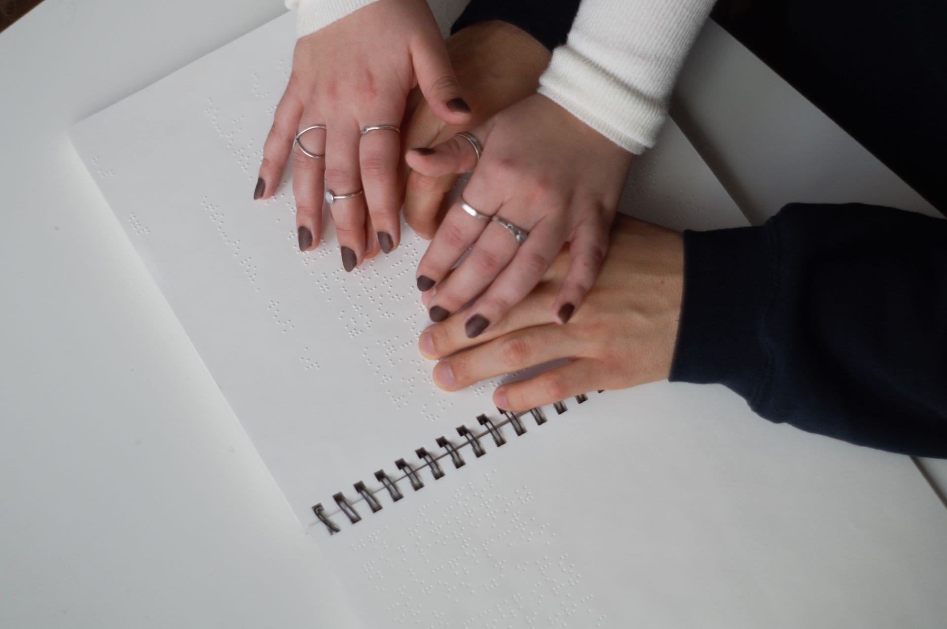 Una persona enseñando a otra cómo leer braille