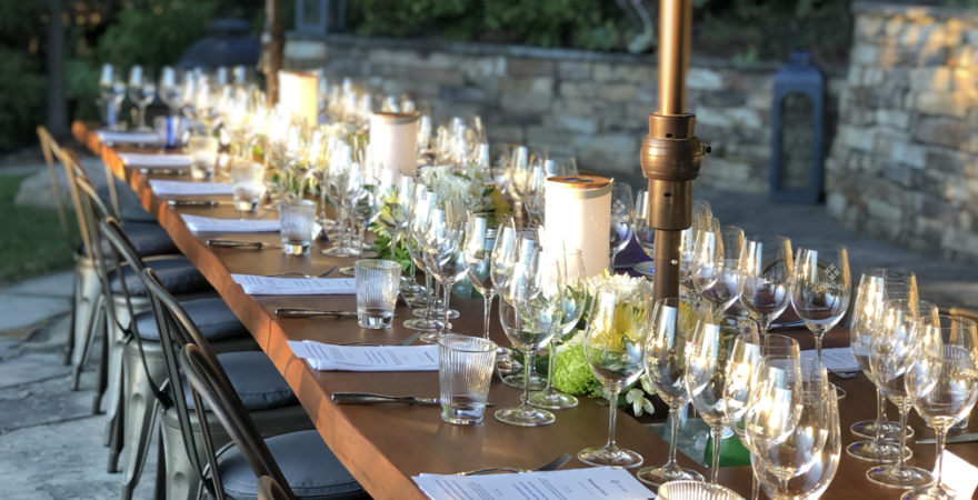 The table is set for dinner with a lot of wine glasses