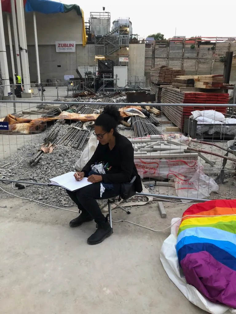 Frau sitzt auf einer Baustelle und zeichnet
