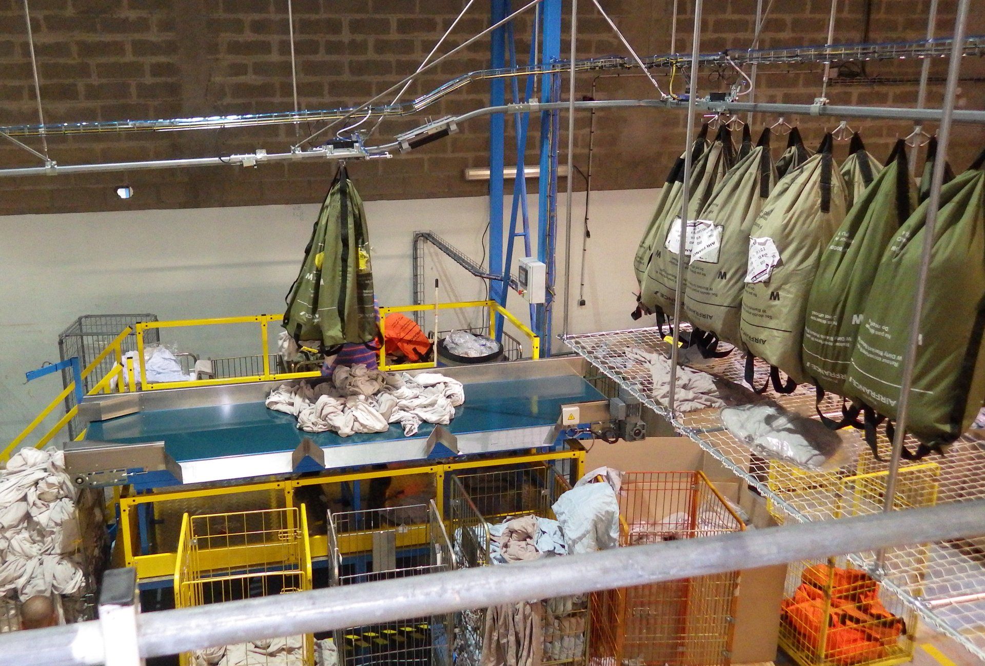 Convoyeur blanchisserie poste de tri sur tapis du linge sale, système aérien de mise à l’unité des sacs