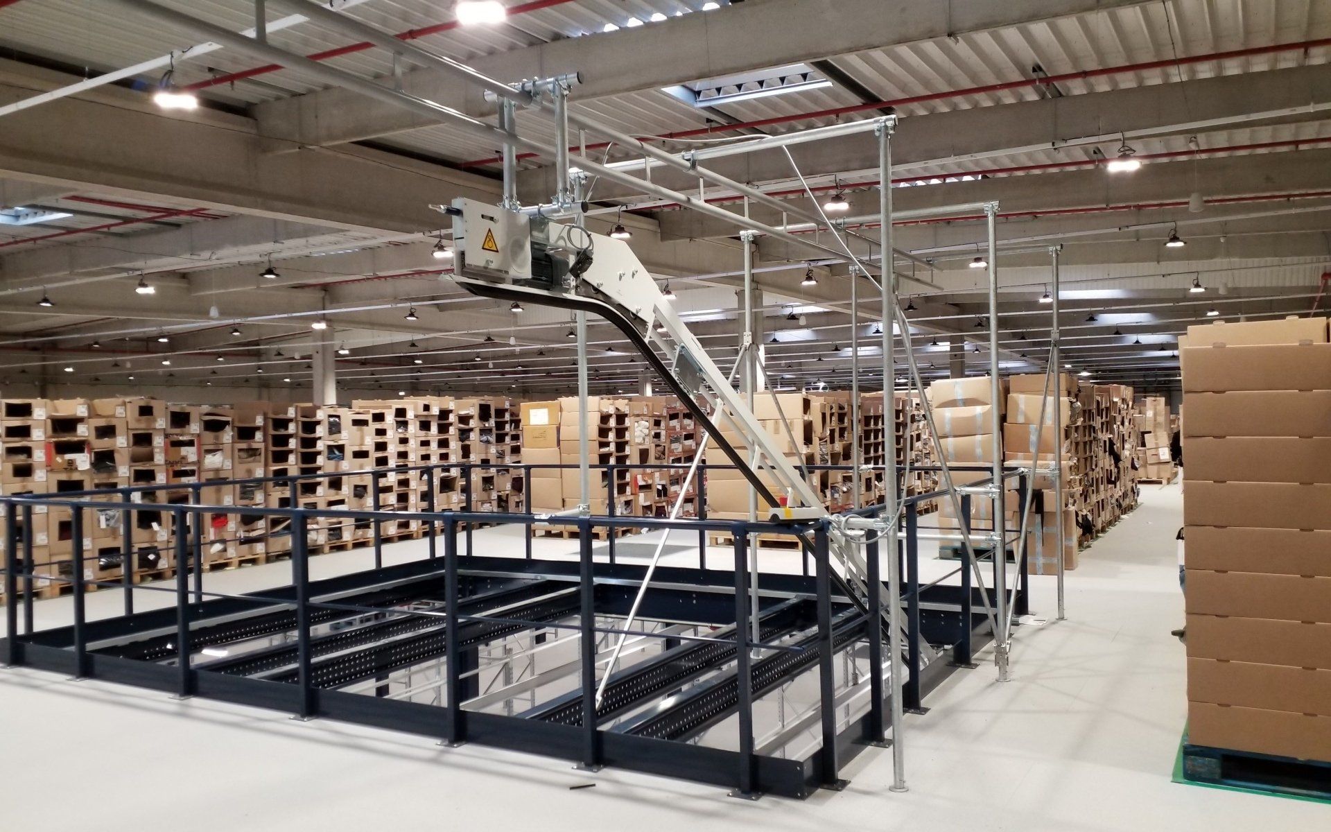 élévateur incliné pour le transfert des vêtements sur cintre en zone de stockage pour plateforme logistique