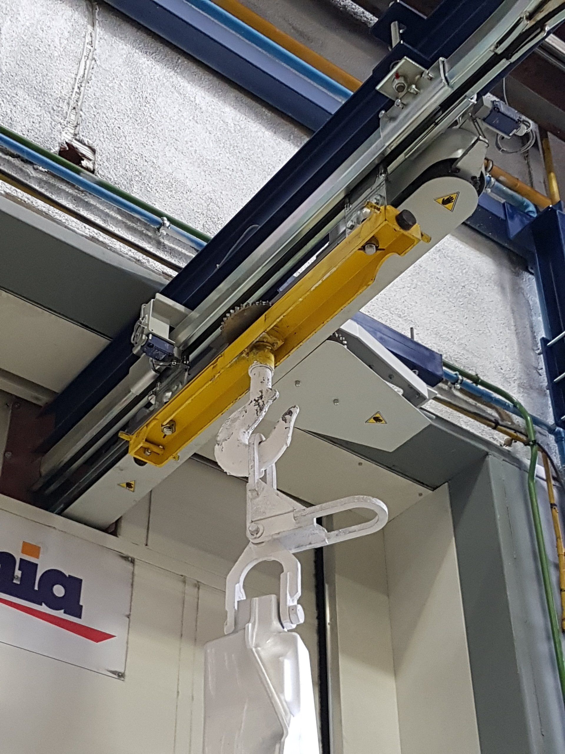 Manutention aérienne en cabine de traitement avec convoyeur aérien à taquet