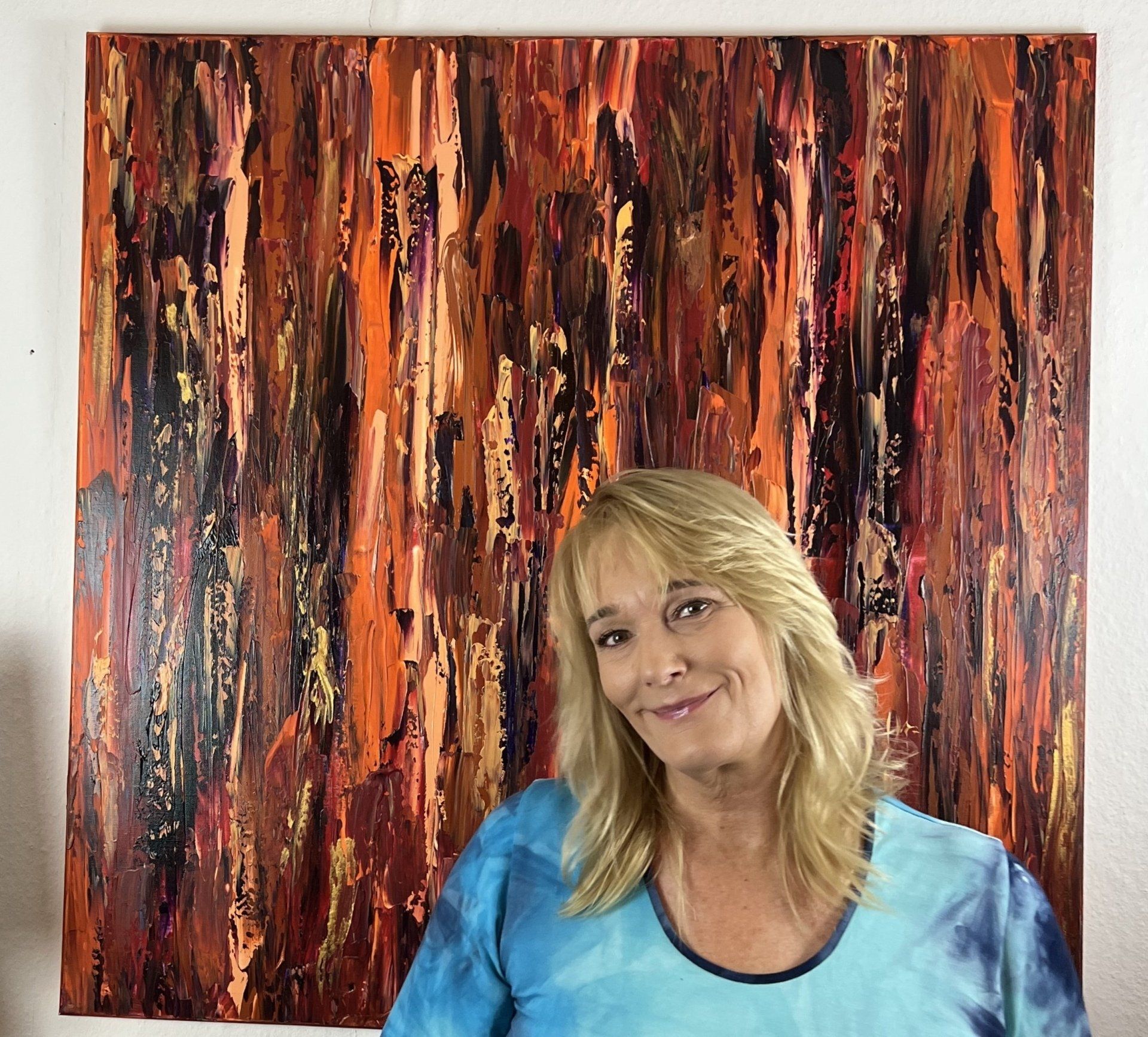 Simone Braun in front of her painting with dark brown tones
