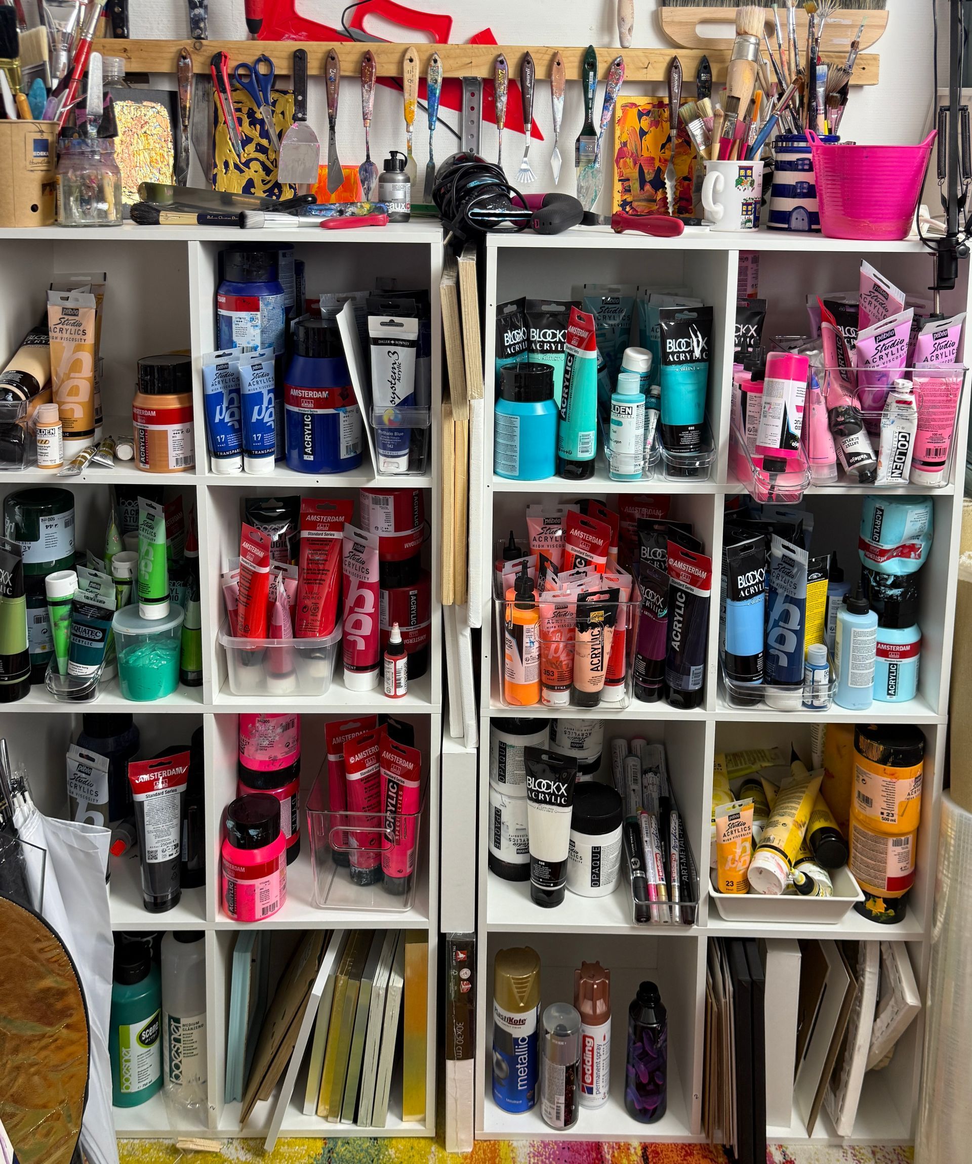 a shelf with lots of paint bottles and tubes