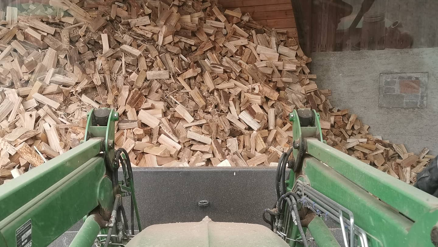 Ansicht aus dem Traktor, wie Brennholz aufgeladen wird.