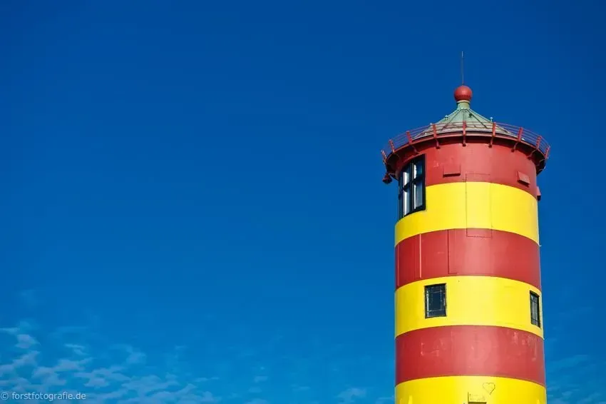 Pilsumer Leuchtturm Rot gelbe Streifen nahe Greetsiel in der Sonne mit blauem Himmel