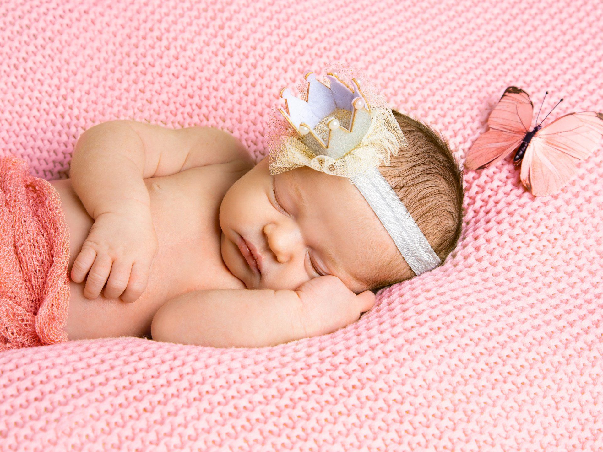 Newborn mit Krone auf rosa Decke
