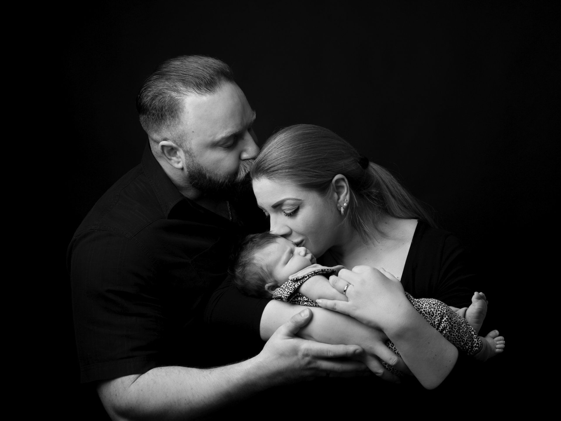 Baby mit Eltern vor scharzem Hintergrund