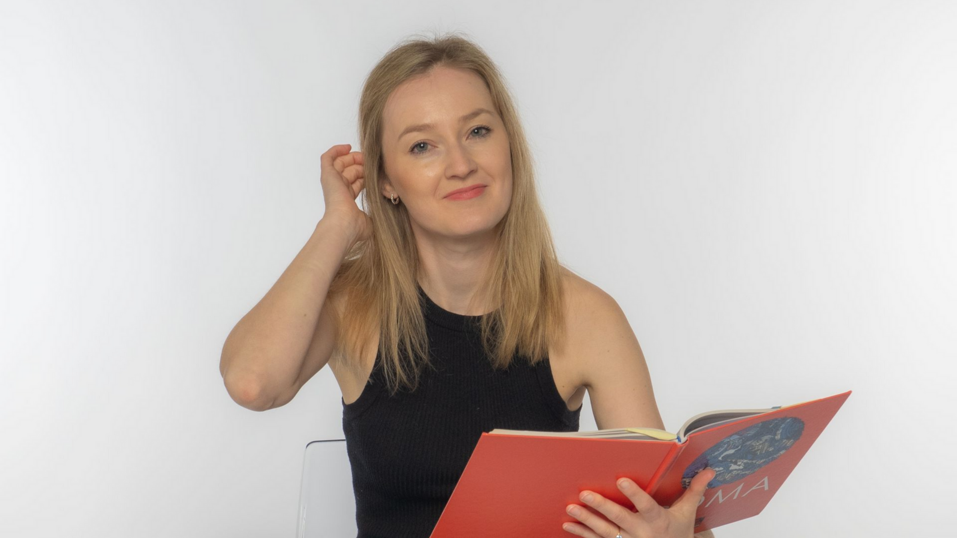 Amelie sitzt mit einem Lateinbuch in der Hand auf einem Stuhl.