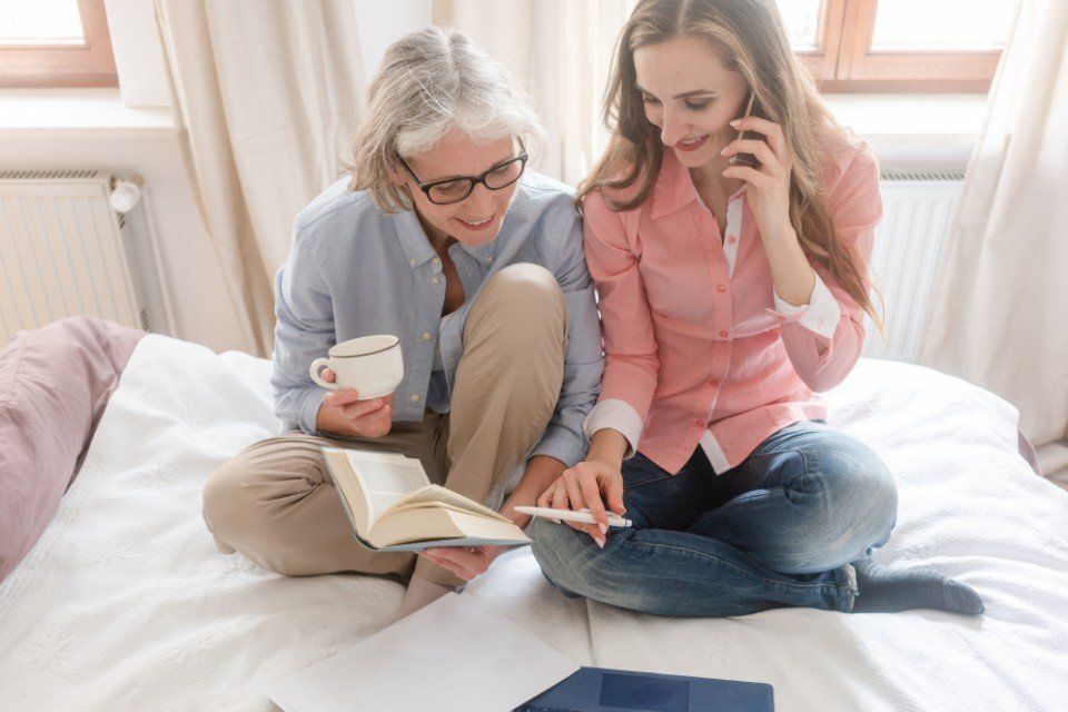 Mutter und Tochter sitzen auf dem Bett und lesen eine Zeitschrift