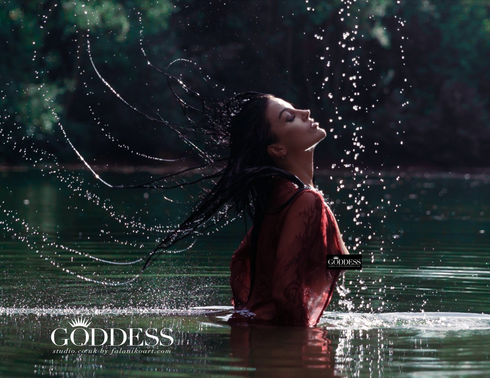 Amber is standing in a lake. She is flicking her hair back, and the water streams in an arc from her, frozen in time.