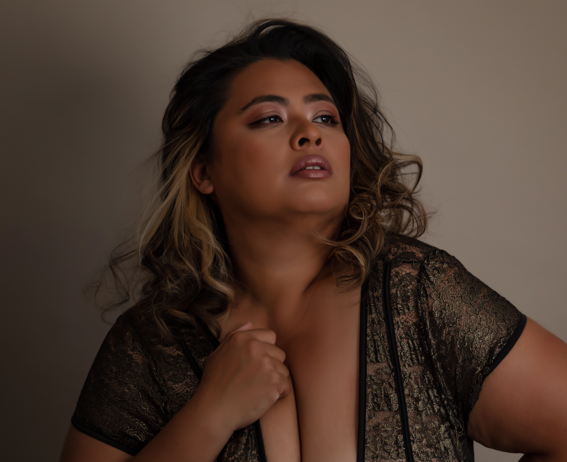 A curvaceous plus-size woman in a gold and black bodysuit looks confident in her photoshoot by Patrick Falaniko.