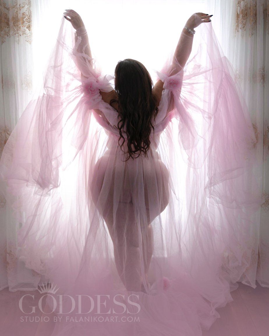 A plus-size curvy goddess silhouetted in french doors in only a voluminous pink robe. Her curves are framed beautifully.