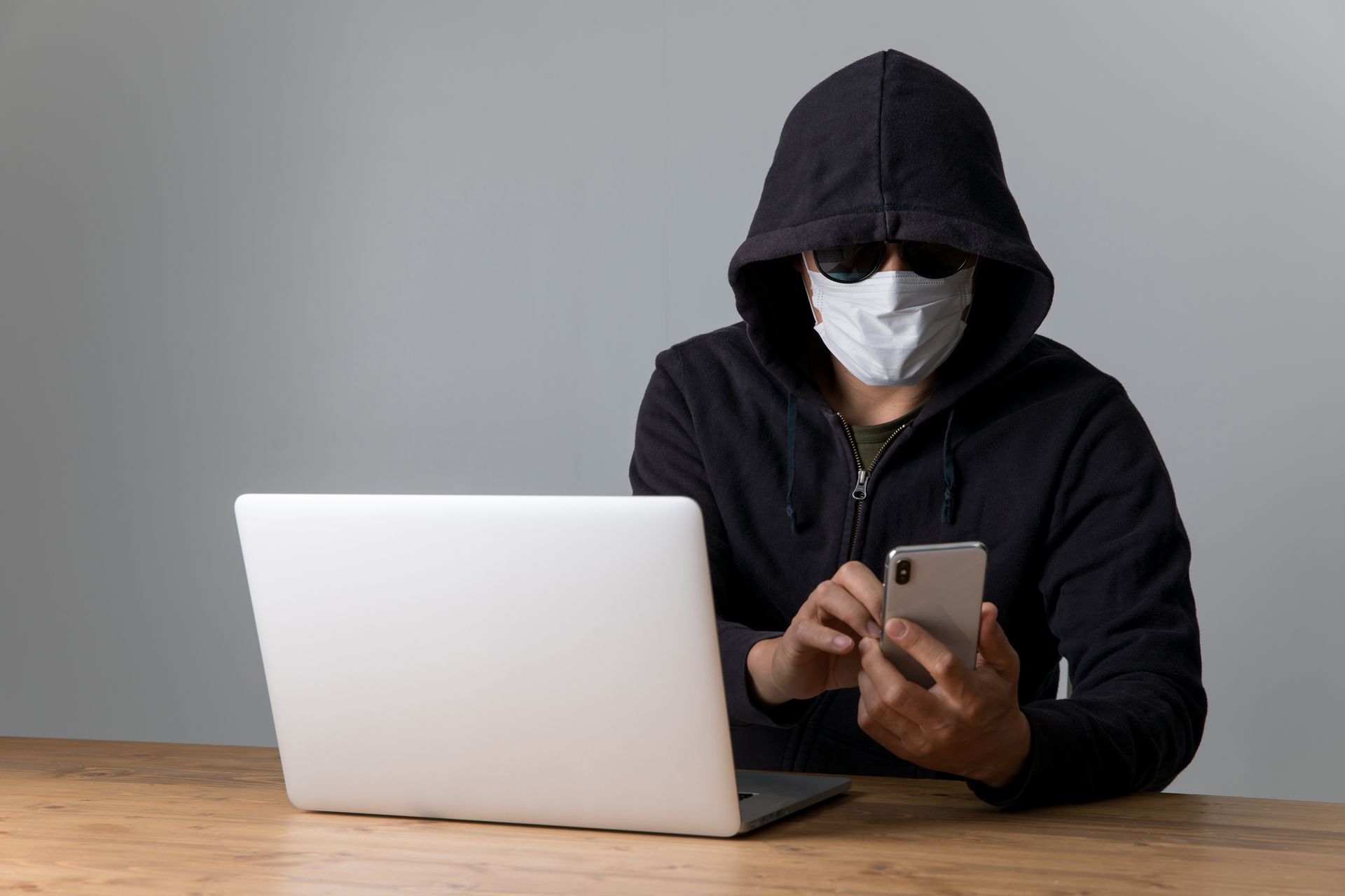 Person sitting at a desk engaged in identity theft and fraud, highlighting the risk of data theft.