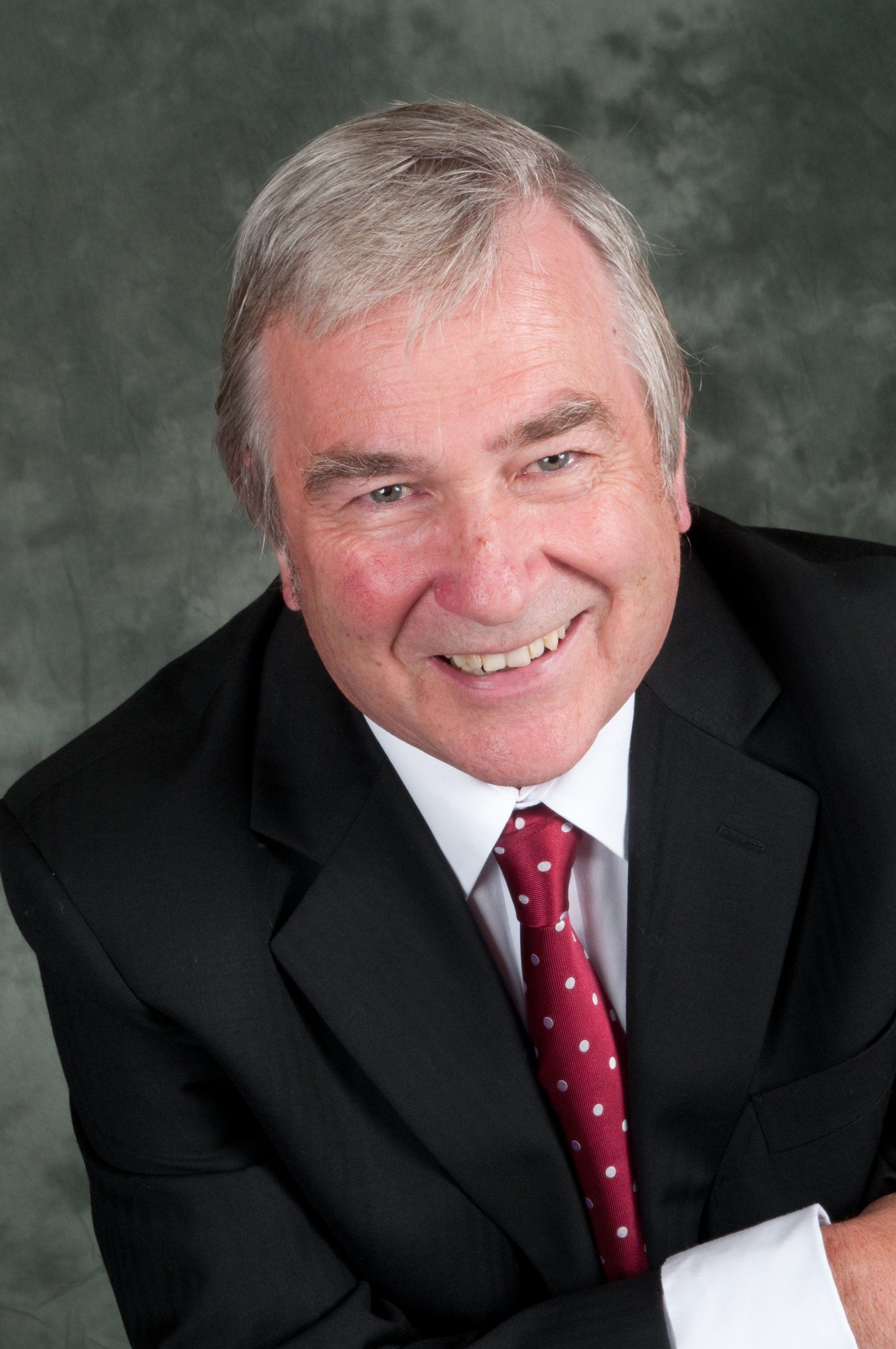 Businessman smiling wearing suit and tie against grey background