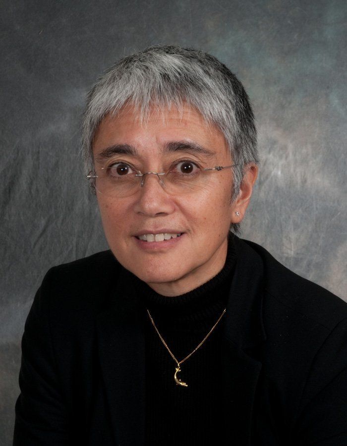 head and shoulders portrait of a lady in a black top against a grey background
