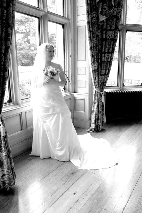 black and white picture of bride standing by window looking back into the room